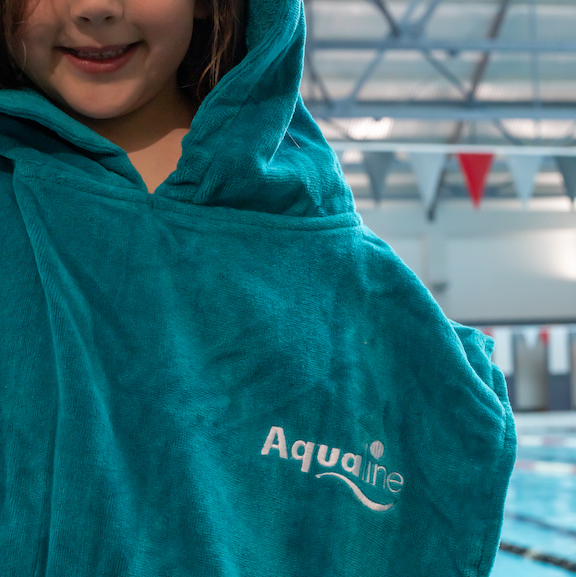 Person wearing a teal Aqualine poncho by a pool