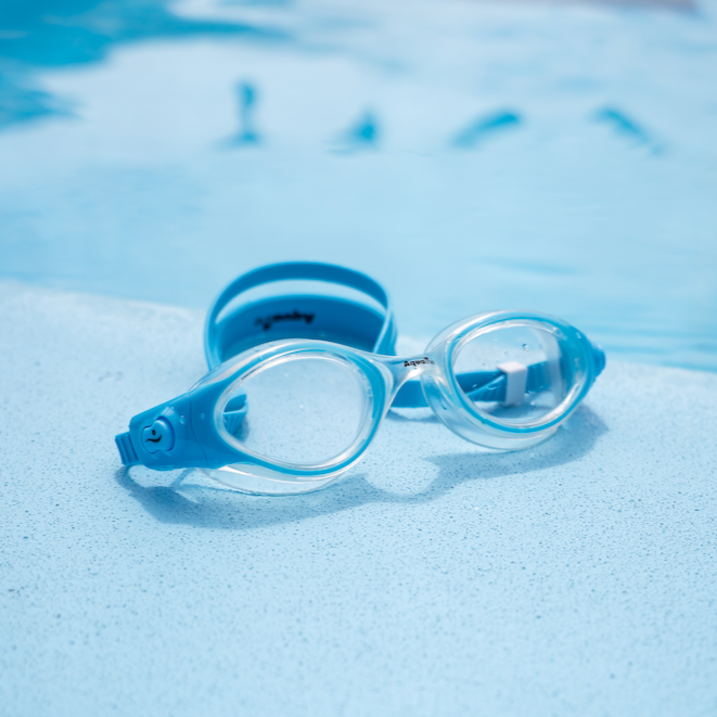 Blue swim goggles on a pool edge with clear water in the background