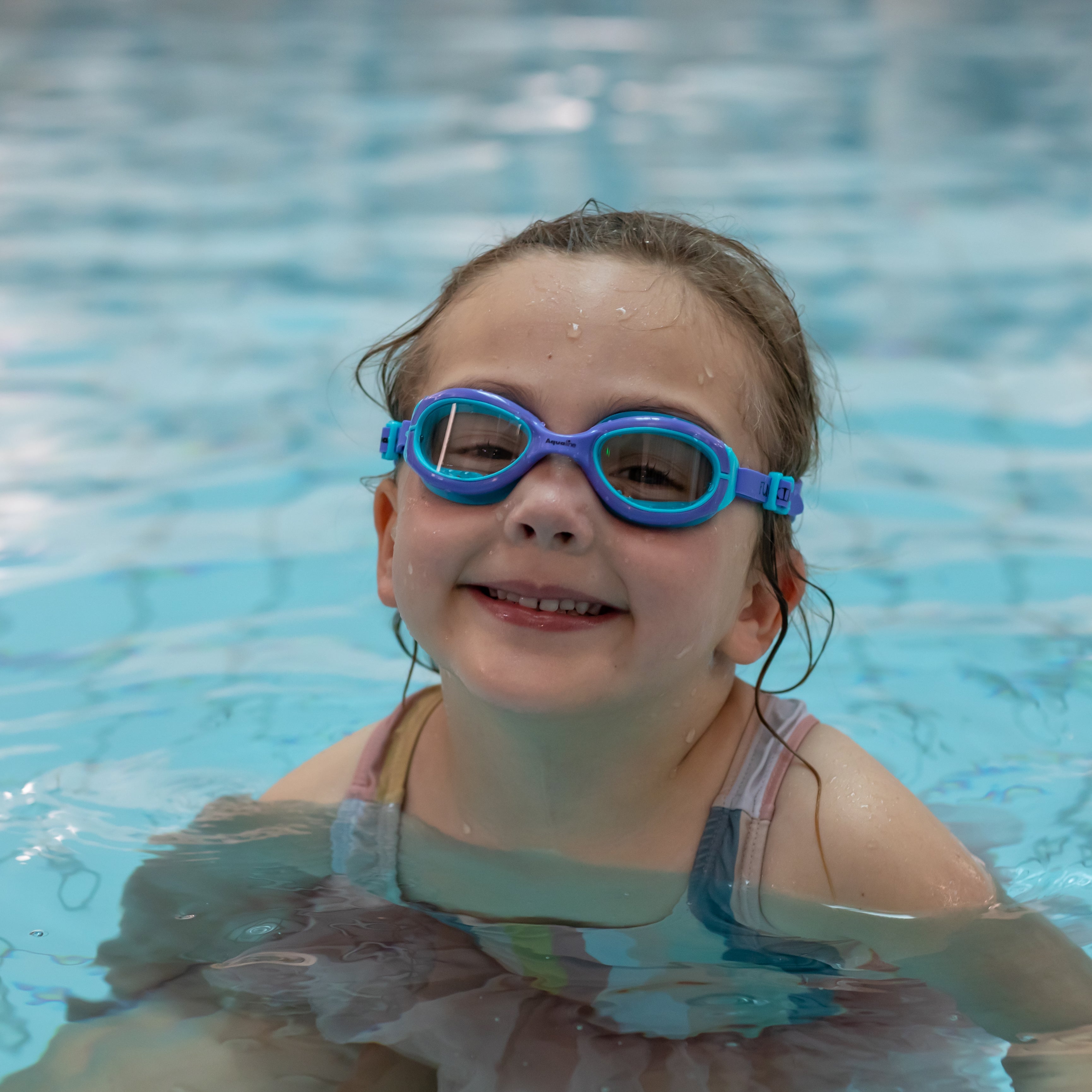 Child wearing blue goggles in a swimming pool